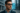 Homme portant des lunettes intelligentes futuristes avec interface holographique bleutée, arrière-plan urbain moderne