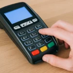 Homme tapant un code sur un terminal de paiement electronique