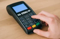 Homme tapant un code sur un terminal de paiement electronique