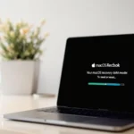 Ordinateur portable affichant un faux écran de récupération macOS avec le texte « macOS Recbok », posé sur un bureau blanc à côté d’une plante en pot et d’une tasse.