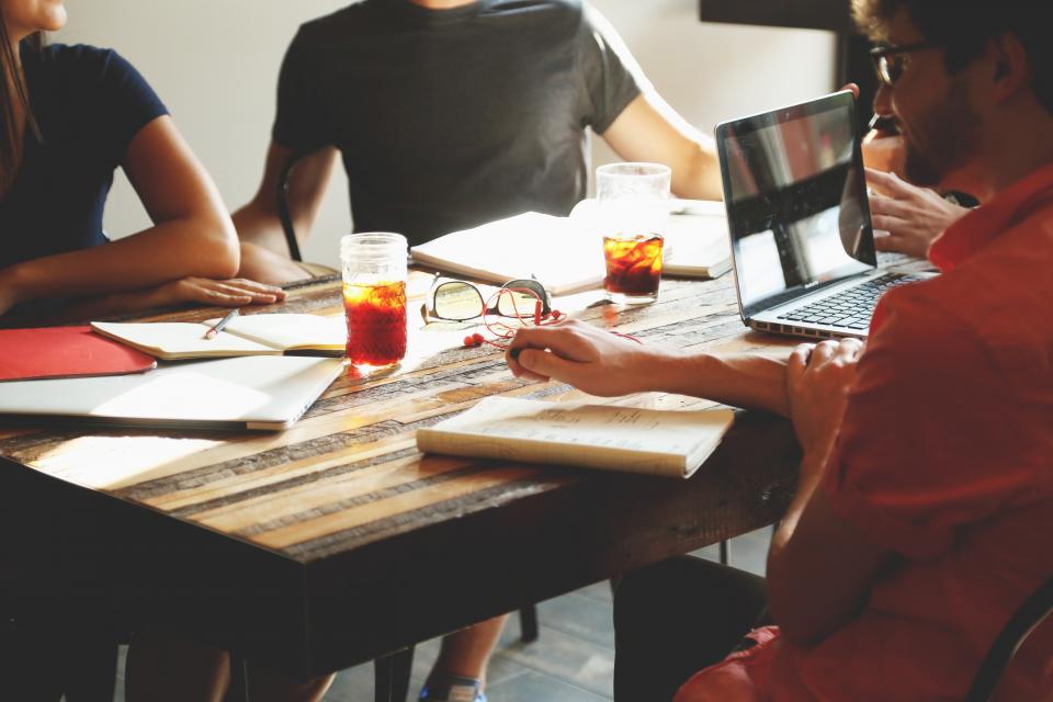 Réunion de travail autour d'une table avec ordinateurs portables, carnets et notes